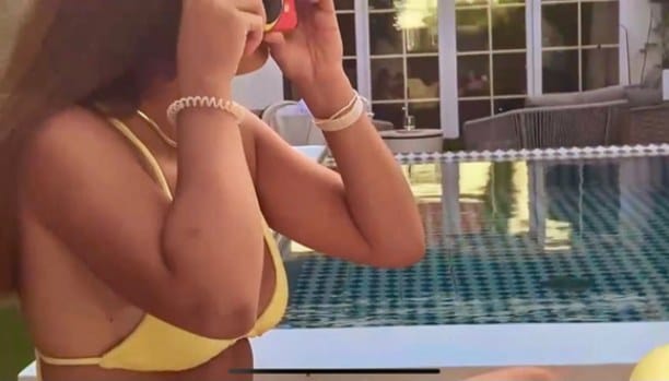 Campaign film still: a woman in a yellow bikini by the pool